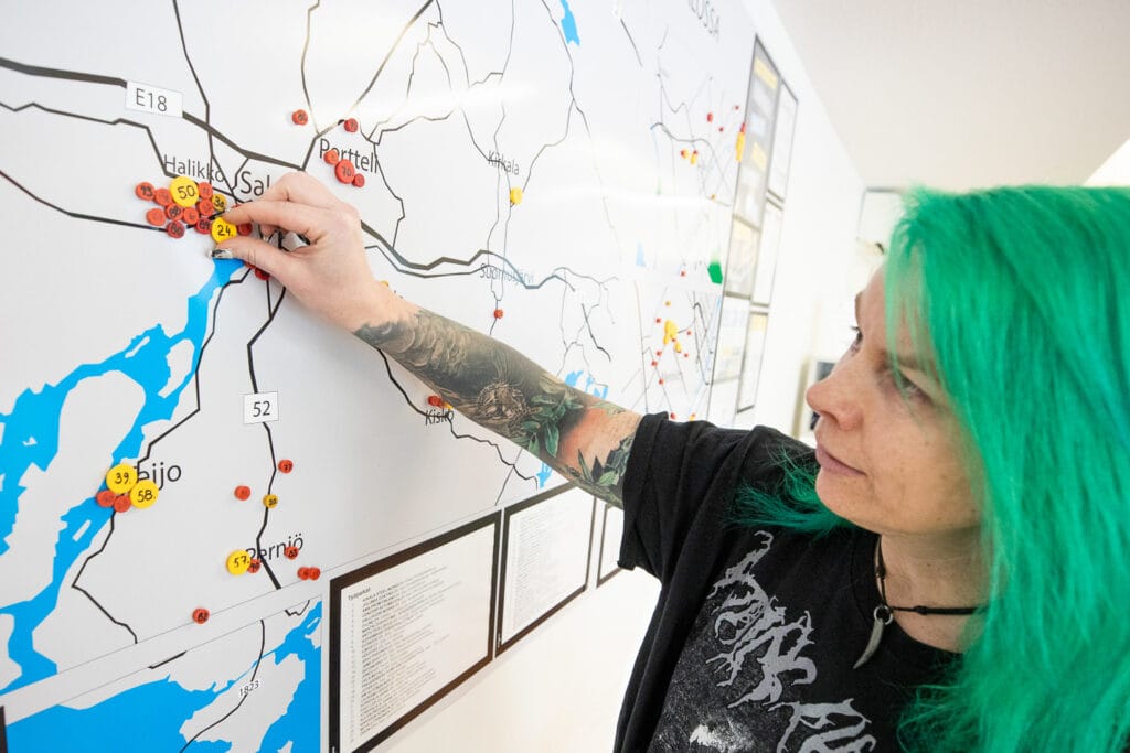 Nainen kiinnittää merkkimagneettia seinällä olevaan karttaan.
