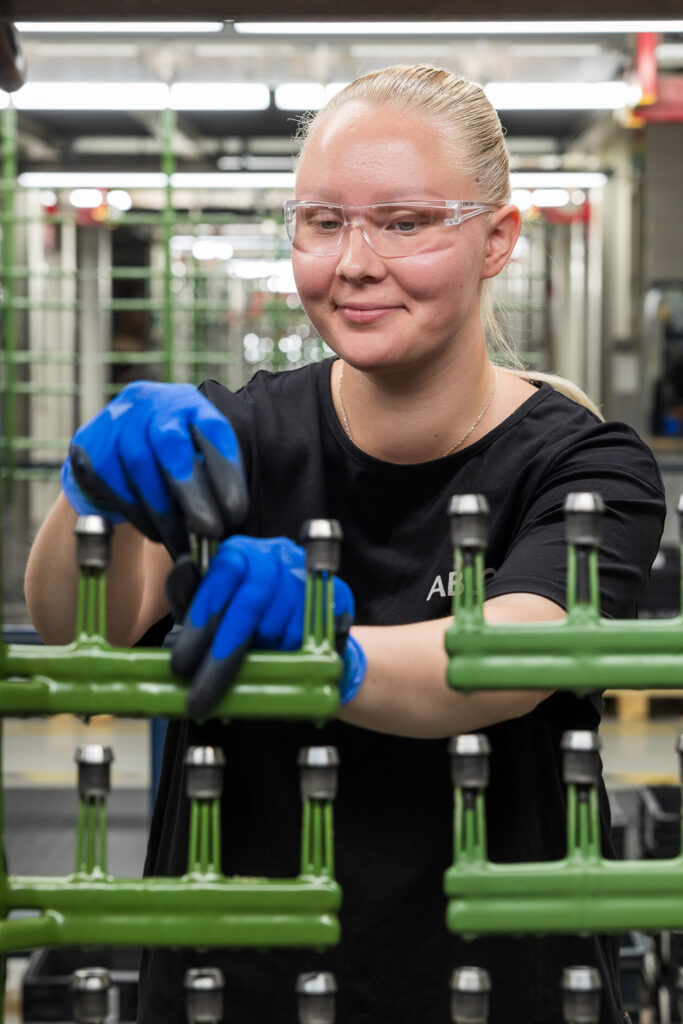 Henkilö asettaa sormenpään kokoisia metalliosia telineeseen.