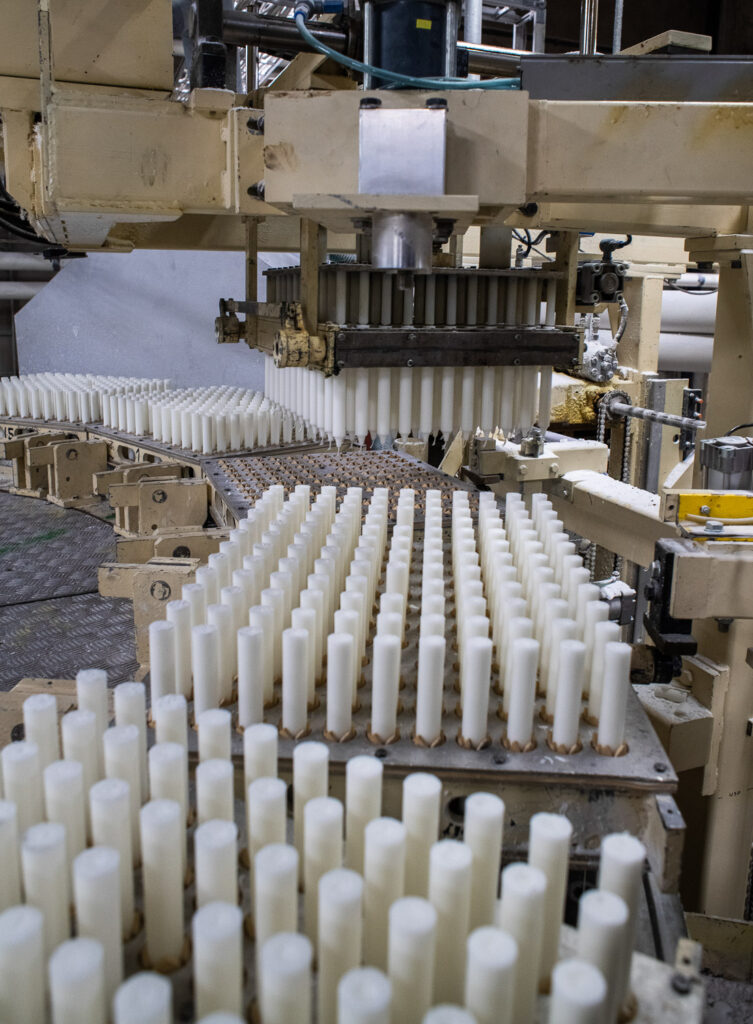 Satoja kynttilöitä kulkee tehtaan tuotantolinjalla.