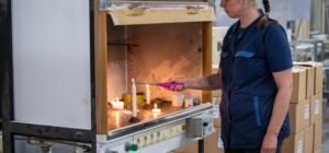 Henkilö sytyttää kynttilöitä tehdasympäristössä.