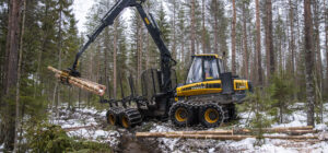 Metsäkone nostaa kaadettuja puita havumetsässä.