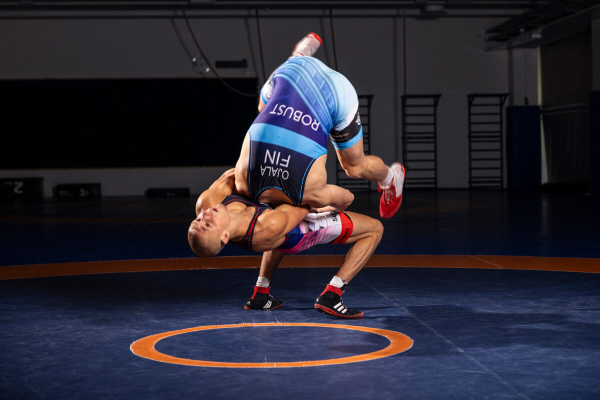 Kaksi painijaa kamppailee kilpailutrikoot päällä. Toinen heittää vastustajaa niskaotteella.