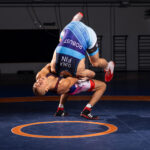 Kaksi painijaa kamppailee kilpailutrikoot päällä. Toinen heittää vastustajaa niskaotteella.