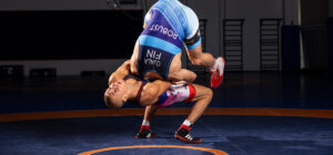 Kaksi painijaa kamppailee kilpailutrikoot päällä. Toinen heittää vastustajaa niskaotteella.