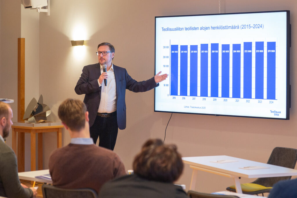 Mies esittelee pylväsdiagrammia teollisten alojen henkilöstömäärän kehityksestä. 