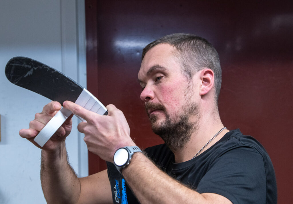 Henkilö teippaa jääkiekkomailan lapaa eristysnauhalla.