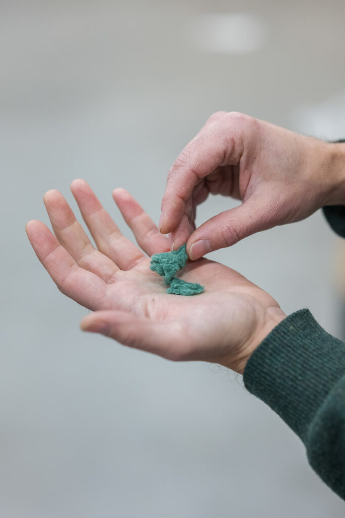 Kädet esittelevät prosessoitua tekstiilikuitua.