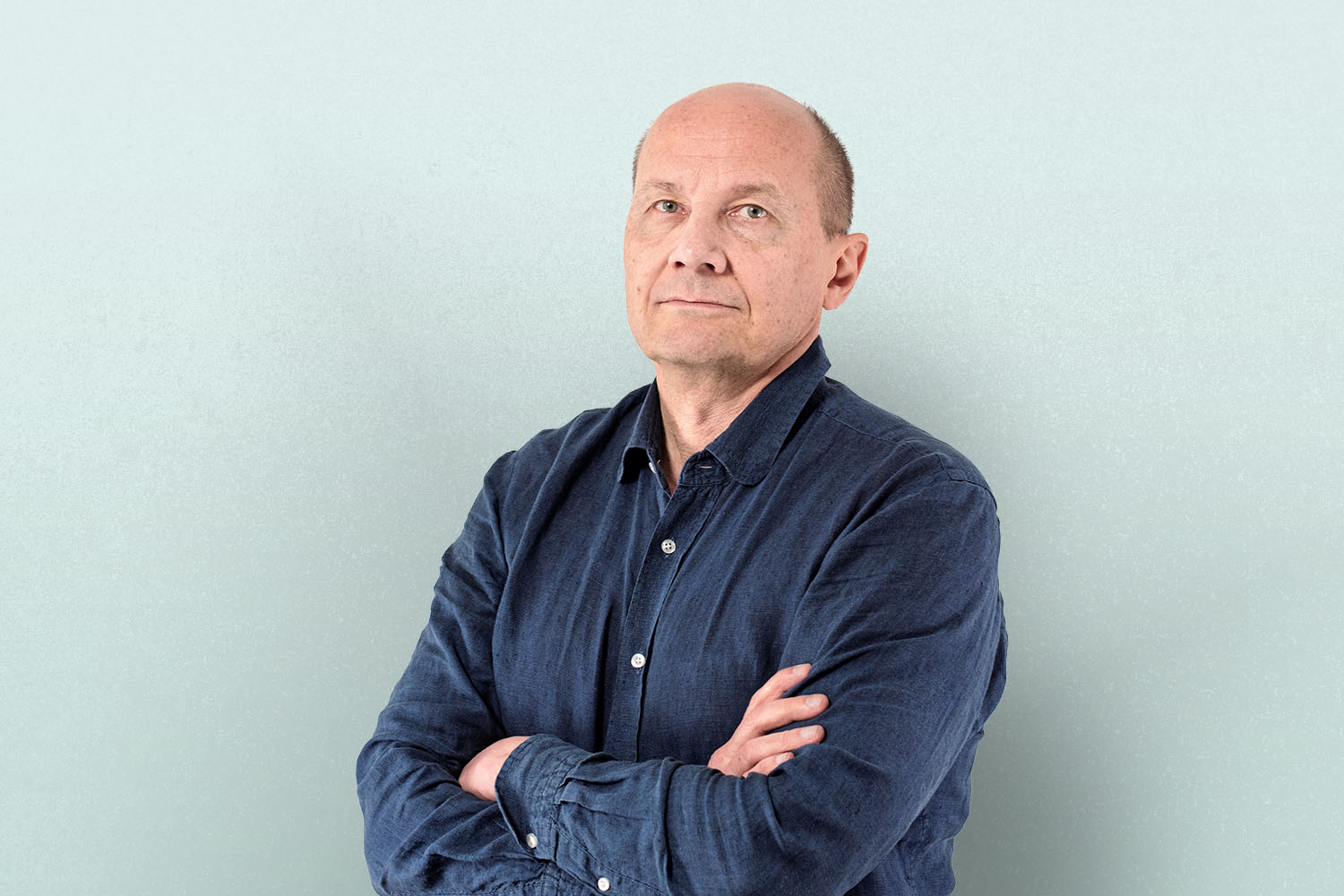 Henkilö seisoo kädet puuskassa ja katsoo kameraan.