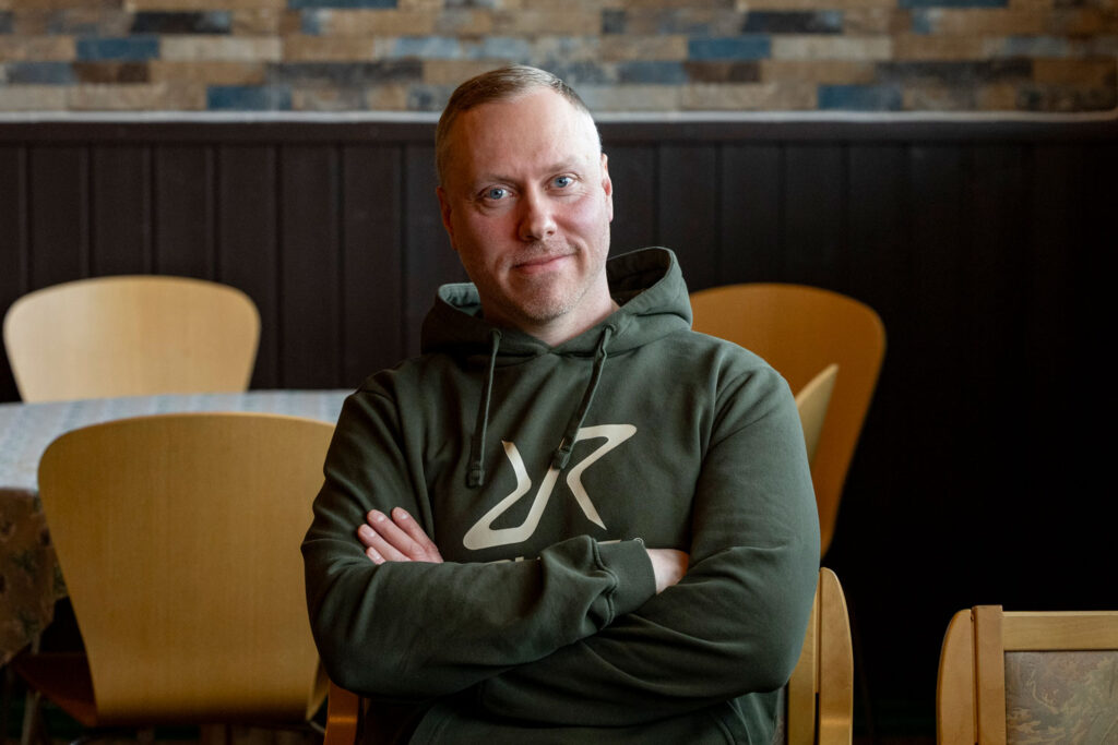 Mies katsoo kameraan ja hymyilee