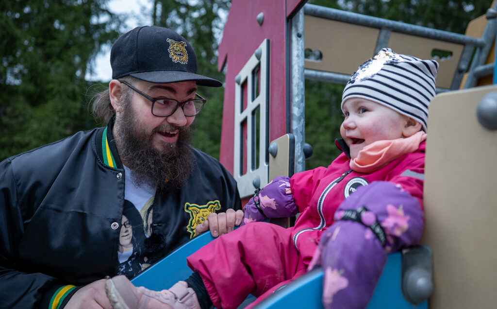 Mies katsoo lasta, joka on liukumäessä.