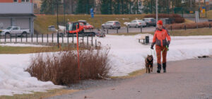 Nainen kävelee koiran kanssa hiekkatiellä