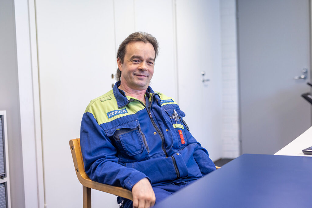 Mies istuu työhaalareissa.