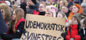 Mielenosoitus, jossa eturivissä henkilö pitelee kylttiä, jossa lukee "udemokratisk svinestreg".