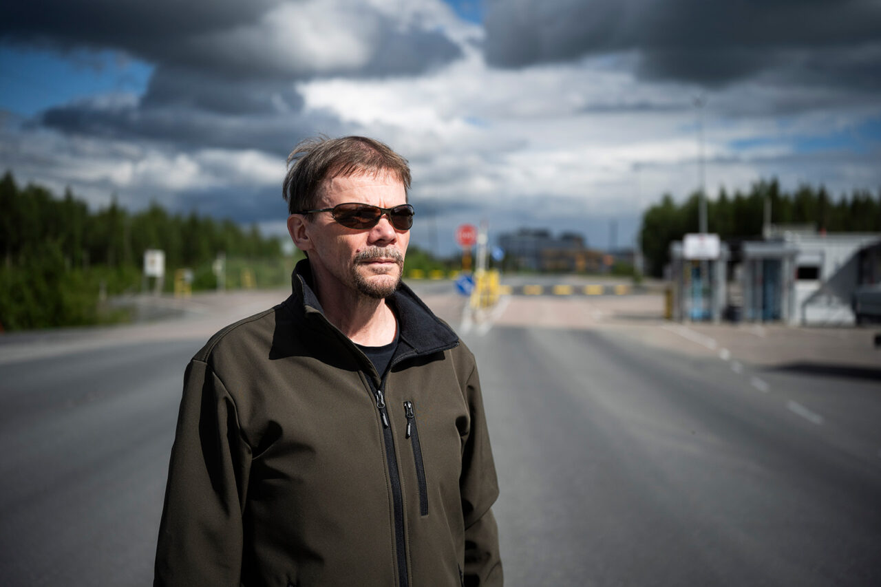 Mies seisoo ulkona ja katsoo sivulle, taustalla kaivosalueen sisäänkäynti.